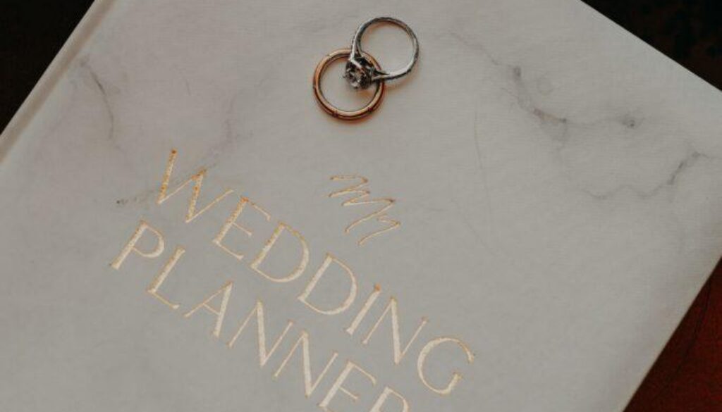“Wedding planner guide with wedding rings on a planning book, representing luxury wedding planning services in Metro Detroit