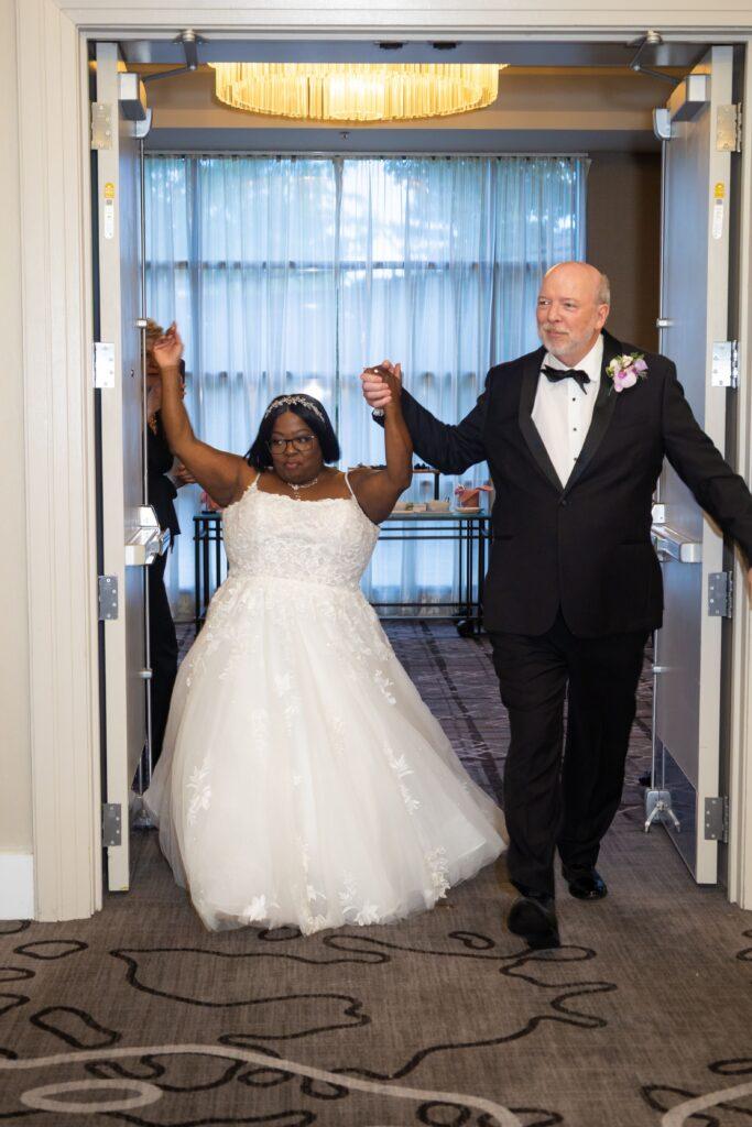 Newlyweds Catrenia and John raise their joined hands as they make their grand entrance into their wedding reception.
