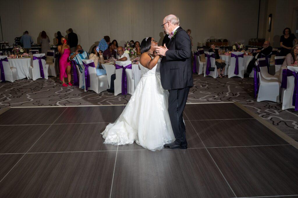Newlyweds Catrenia and John smile at each other while sharing their first dance during their wedding reception.